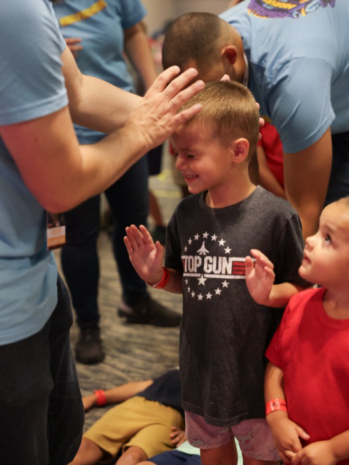 A leader praying over a little boy