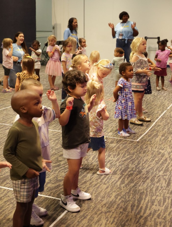 Preschoolers worshipping with hands raised