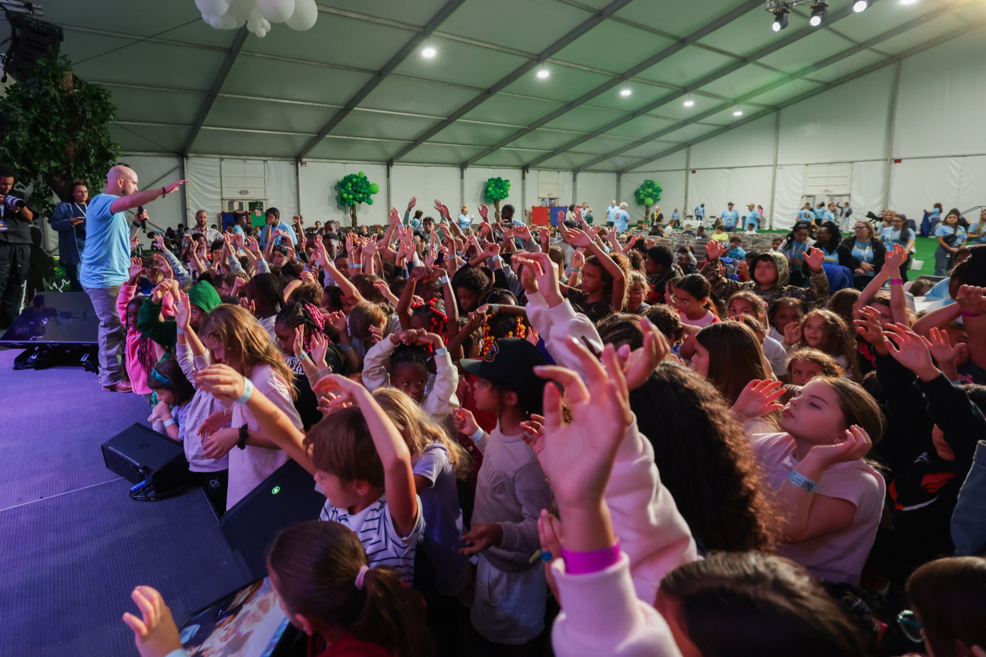Children worshipping with hands raised in the Kids Week tent
